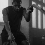 Focused man in gym intensively training with ropes indoors.